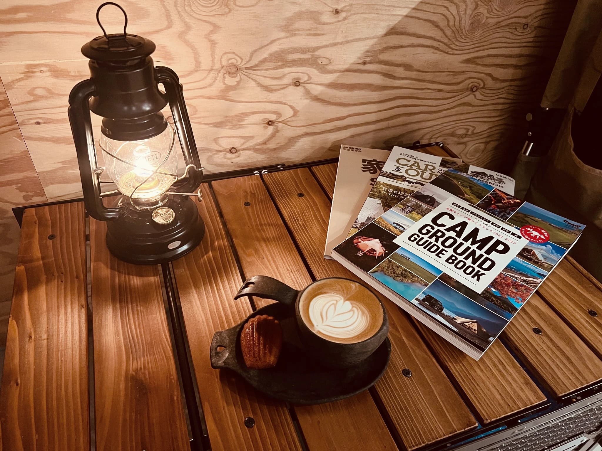 ランタンとCAMP GROUND GUIDE BOOK、KUPILKAのカップに入ったコーヒー